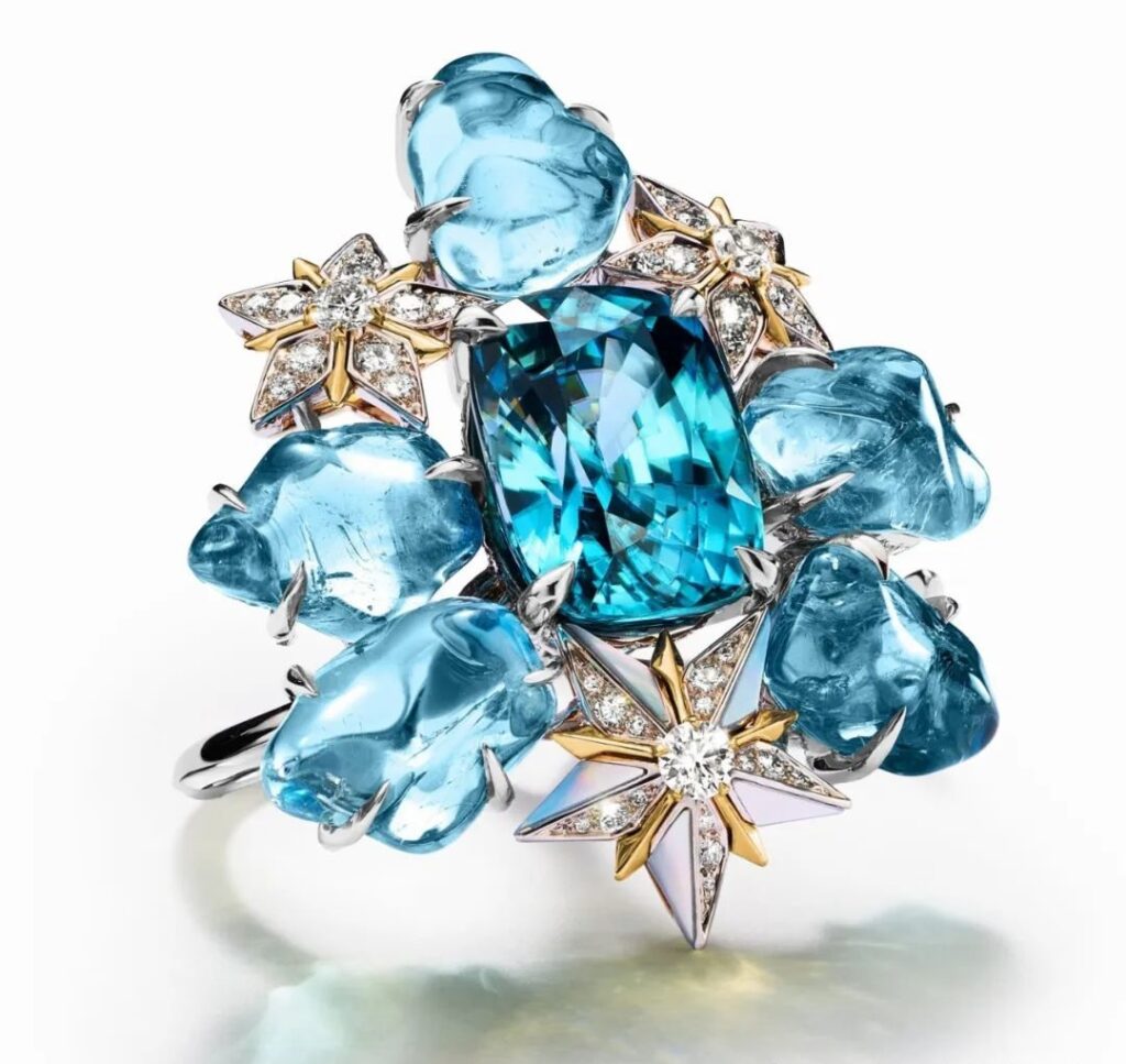 Iconic Star Gold Ring, by Tiffany:
This ring, made of platinum and yellow gold, features a central blue zircon of over 26 carats, surrounded by blue sapphires totaling over 32 carats, mother-of-pearl, and diamonds.