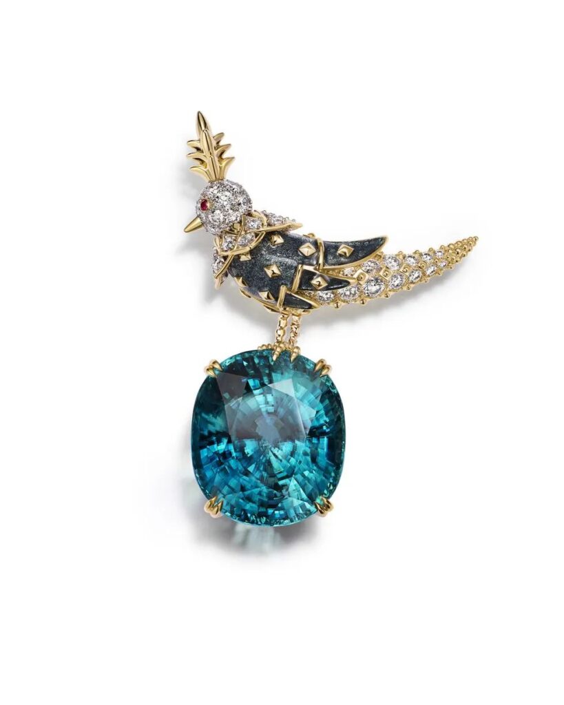 Jean Schlumberger High Jewelry Collection (JEAN SCHLUMBERGER BY TIFFANY) RAINBOW BIRD ON A ROCK brooch: Platinum and 18K yellow gold set with a blue zircon weighing over 80 carats, gray enamel, rubies, and diamonds.