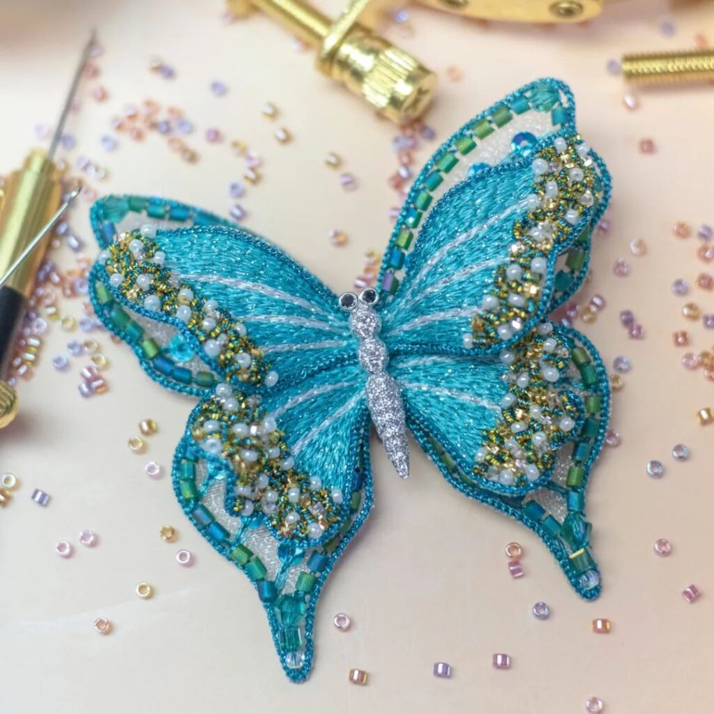 La broderie's embroidered butterfly brooch, set with colored gemstones.