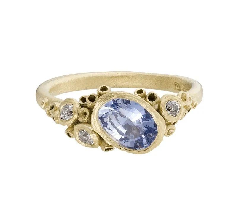 Barnacle cluster gold ring, by Ami Pepper.
The main stone is an oval-cut light blue sapphire, accented with diamonds.