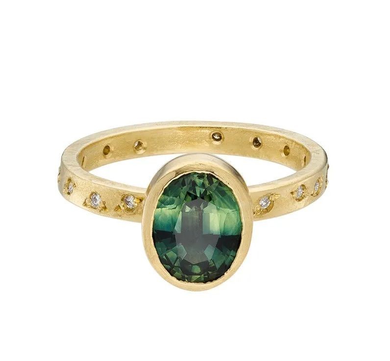 Solitaire gold ring, by Shimara Carlow.
The main stone is an oval-cut green sapphire, accented with diamonds.