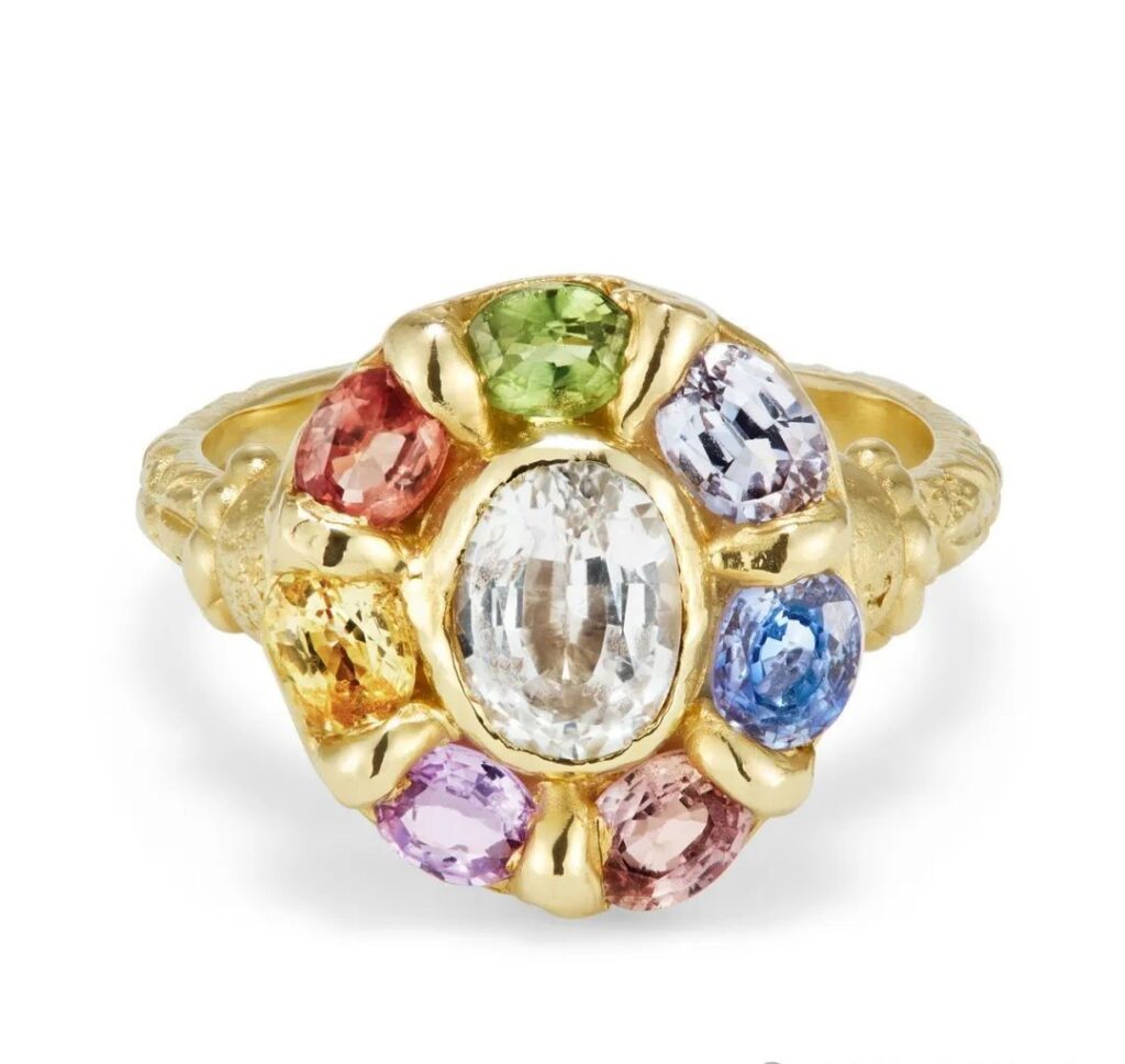 Rainbow Mega Halo gold ring, by Ciara Bowles.
The center stone is a 1-carat oval-cut white sapphire, surrounded by oval-cut colored sapphires with a total weight of 2.6 carats.