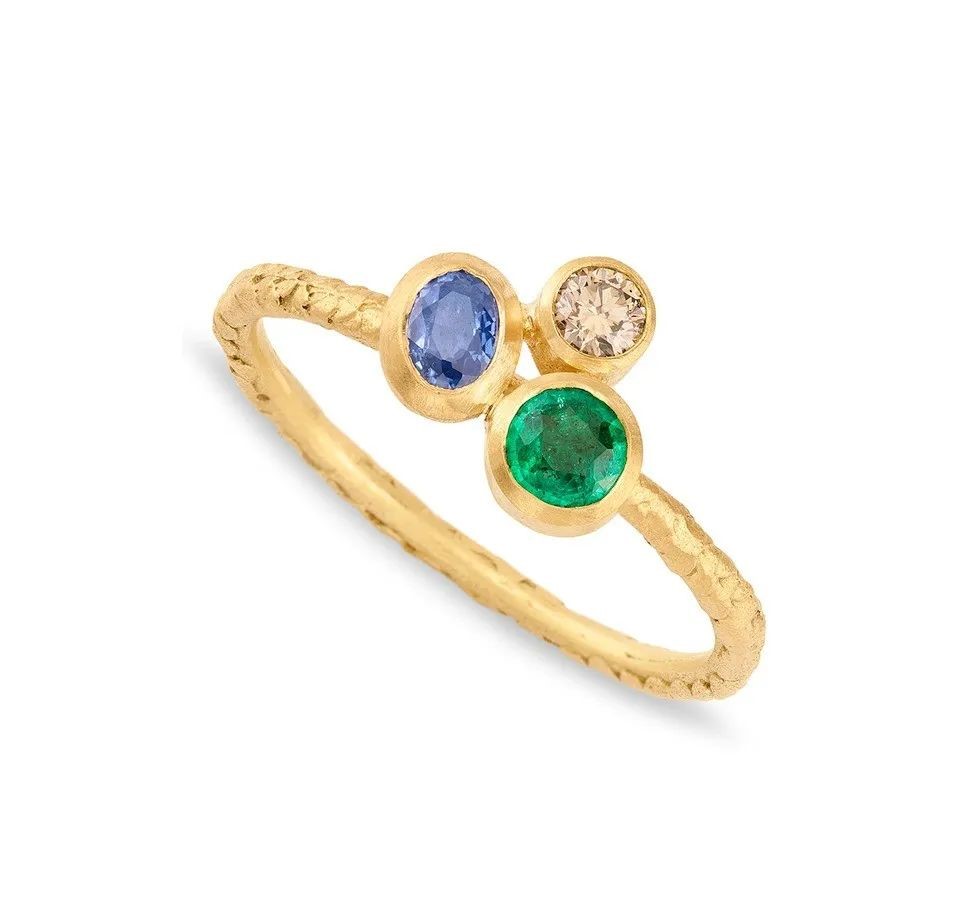 Catkin gold ring, by Alison Macleod.
Set with an oval-cut Sri Lankan sapphire, round-cut emeralds, and champagne diamonds.